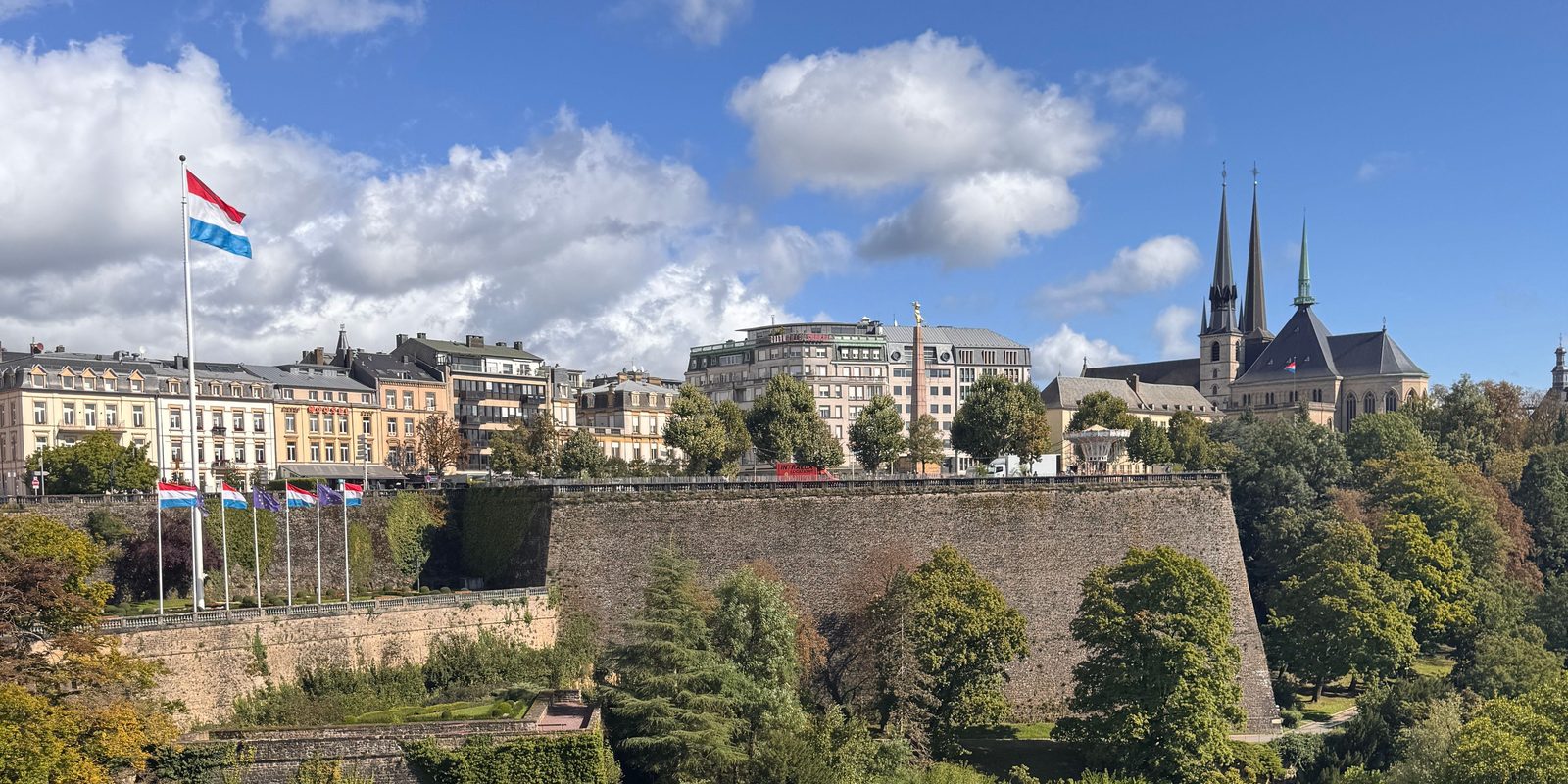 Drapeau luxembourgeois flottant devant les remparts de la vieille ville de Luxembourg et les flèches de la cathédrale Notre-Dame