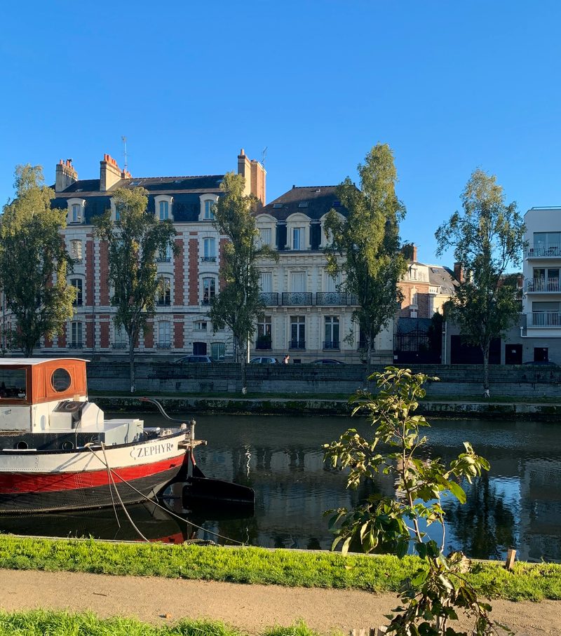 Péniche amarrée sur les quais de la Vilaine à Rennes, devant des immeubles bourgeois en pierre et brique